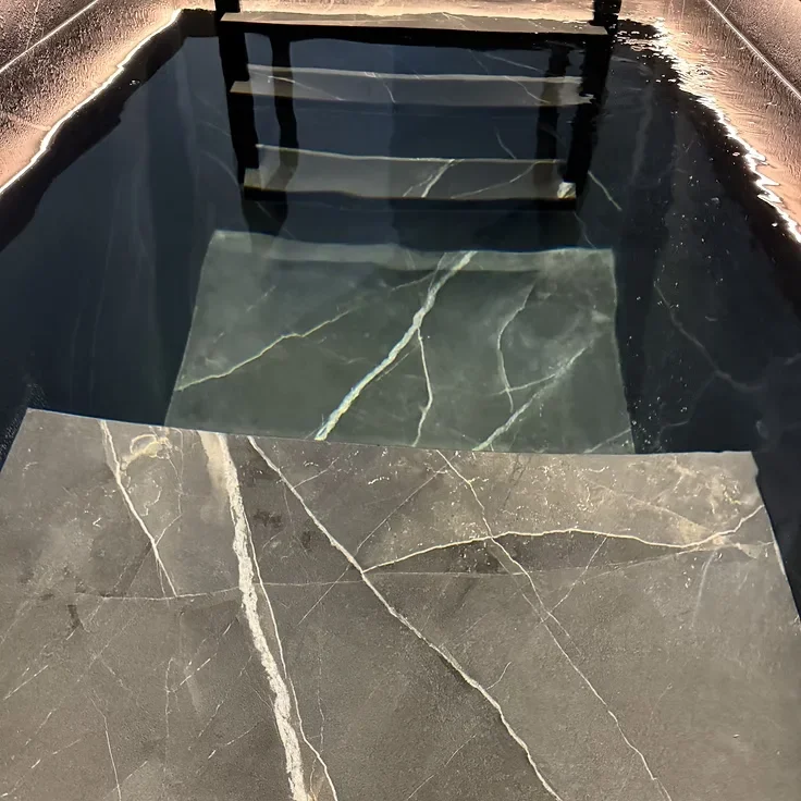Degraus interiores em mármore cinzento de uma banheira de imersão Nordic Vitality, vistos dentro de água