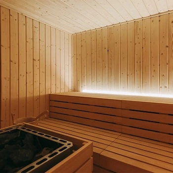 Sauna interior em painéis de madeira com bancos largos e iluminação indireta
